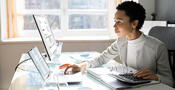 A woman using multiple computers at her desk