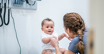 A pediatrician playing with a baby during a visit