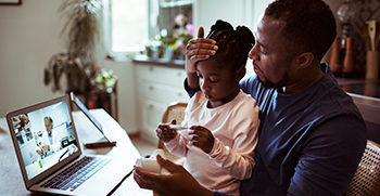 A father and his young daughter on a telehealth sick visit on a laptop computer