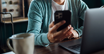 A close-up of a woman on her phone and laptop