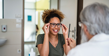 A woman trying on her new glasses for her eye doctor