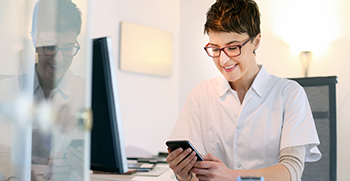 A woman sitting and typing on her phone at her desk