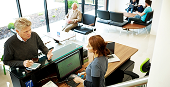 A patient checking in for a cardiology appointment with a nurse at the front desk